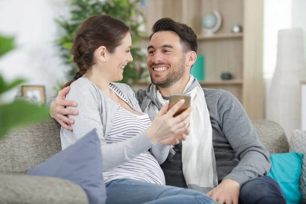 Šťastný Muž Jeho Těhotná Žena Chytrými Telefony Doma — Stock fotografie
