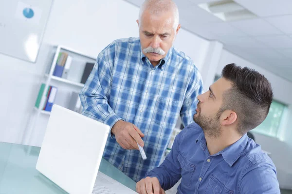 Senior Man Geeft Instructies Aan Collega Met Behulp Van Laptop — Stockfoto