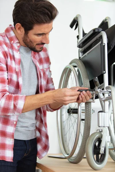 Junger Schöner Mann Repariert Einen Rollstuhl — Stockfoto