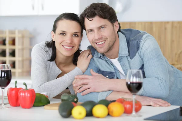 幸せカップル抱擁とキッチンで赤ワインを飲む — ストック写真