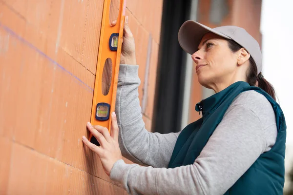 Vrouw Metselaar Houden Van Een Waterpas Een Baksteen Muur — Stockfoto