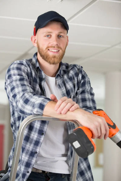 Gelukkig Mannelijk Bouwer Staande Ladder Met Boor — Stockfoto