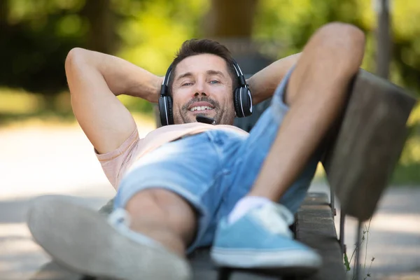 Homem Usando Fones Ouvido Colocado Banco Parque — Fotografia de Stock