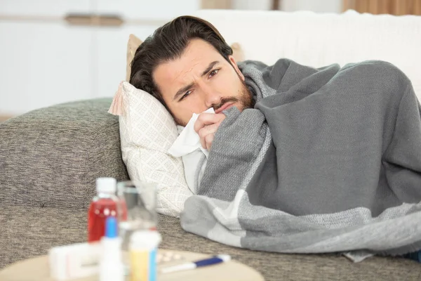 Άρρωστος Άντρας Ξαπλωμένος Στον Καναπέ Στο Σπίτι Και Φυσώντας Μύτη — Φωτογραφία Αρχείου