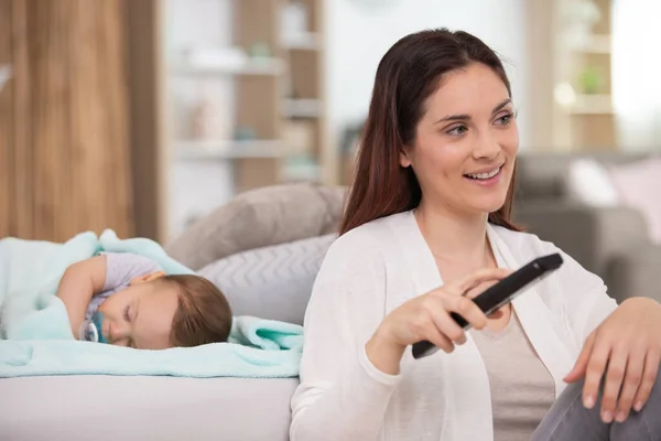 Mother Watching Television Seelping Newborn Baby — Stock Photo, Image