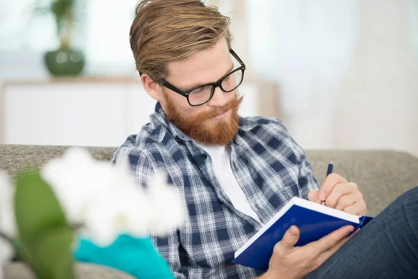 Junger Mann Mit Brille Liest Ein Buch Auf Dem Sofa — Stockfoto