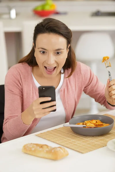 Pretty Female Holds Smartphone While She Eats Lunch —  Fotos de Stock