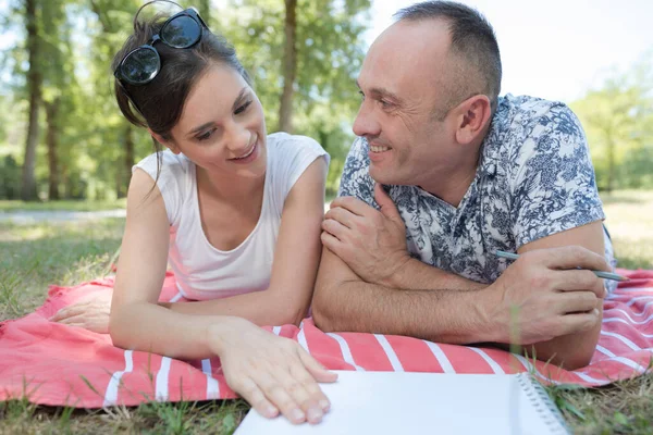 Couple Posé Sur Couverture Sur Herbe Regardant Carnet — Photo