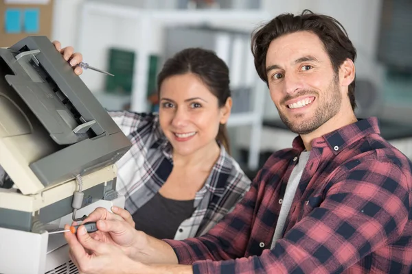 working couple repairing a photocopier machine