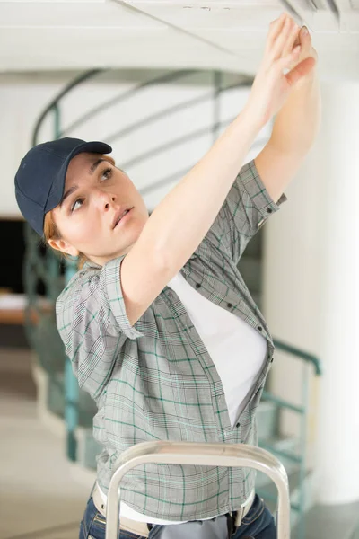 Woman Ladder Fitting Light Bulb New House — Stock Photo, Image