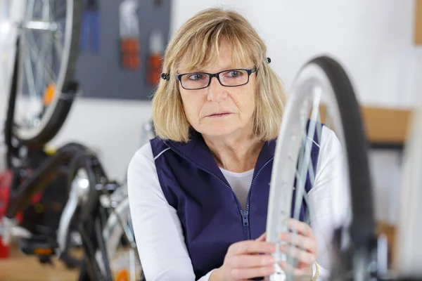 Mature Woman Repairing Bicycle Wheel — Stock Photo, Image