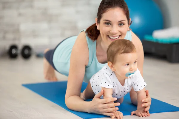 young mother does physical yoga exercises together with her baby