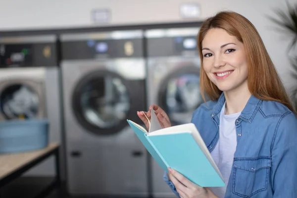 Glad Kvinnlig Läsning Bok Medan Hon Tvättar Tvättomat — Stockfoto