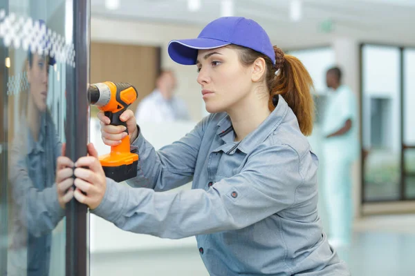 Mujer Joven Utilizando Taladro Energía Ventana — Foto de Stock