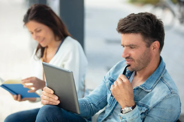 Pareja Leyendo Libro Tableta Mientras Espera Transporte Público —  Fotos de Stock