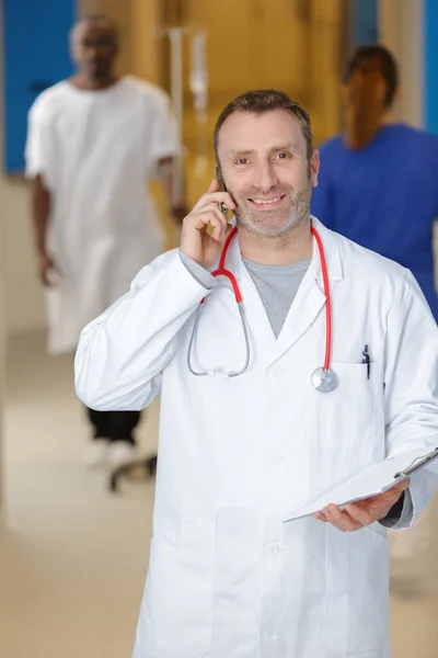 Γιατρός Κρατώντας Ένα Κινητό Τηλέφωνο Και Κοιτάζοντας Την Κάμερα — Φωτογραφία Αρχείου