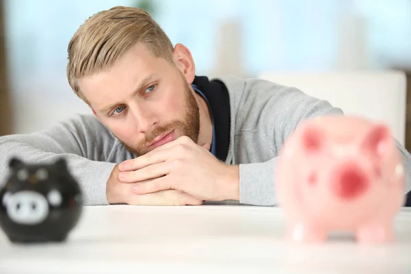 Homem Contemplativo Olhando Para Maior Dois Piggybanks — Fotografia de Stock