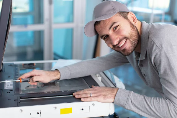 年轻的男技师正在修理一台打印机在办公室 — 图库照片