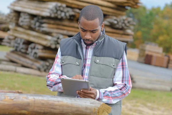 Man Met Tablet Naast Stapel Hout — Stockfoto