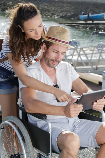 Vrouw Helpen Gehandicapte Man Tablet Buiten Gebruiken — Stockfoto