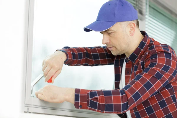 ドライバーを屋内でプラスチック窓を修復する建設労働者 — ストック写真