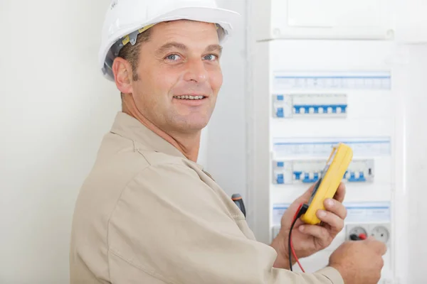 Medelålders Elektriker Använder Multimeter Fusebox — Stockfoto