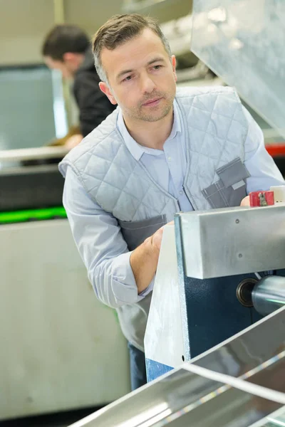 portrait of man cutting paper in factory