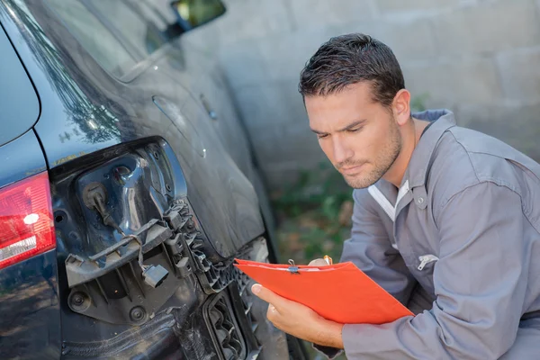 Mechanic inspecting damaged car — Stock Photo, Image