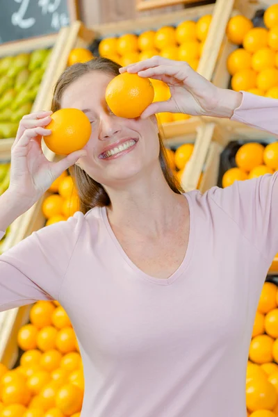 Игривая женщина закрывает глаза апельсинами — стоковое фото