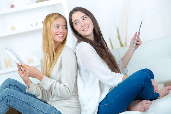 Girls sat back to back on a sofa — Stock Photo, Image