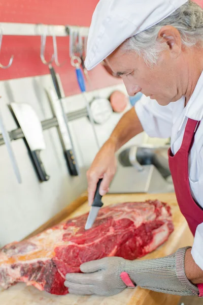 Butcher skilfully preparing a cut of beef — Stock Photo, Image