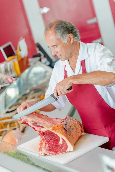 Slager snijden een grote knippen van rundvlees — Stockfoto