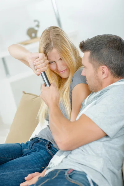 Pareja juguetona peleando por el control remoto de la TV —  Fotos de Stock