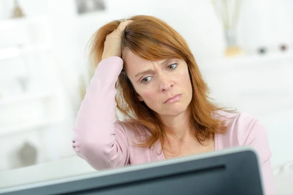 Vrouw kijken naar haar computerscherm benadrukt — Stockfoto