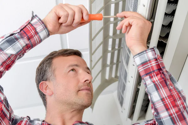 Homem reparando uma unidade de ar condicionado — Fotografia de Stock