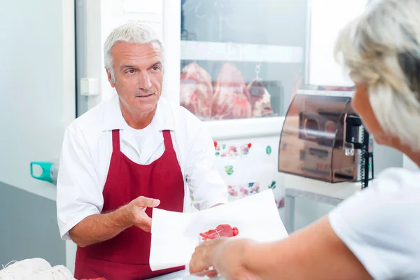 Butcher handing meat to customer — Stock Photo, Image