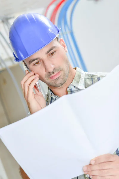 Man on phone looking at plans — Stock Photo, Image