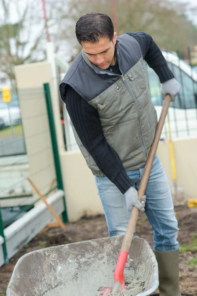 Bauarbeiter mischt Zement in einer Schubkarre — Stockfoto