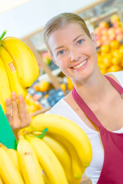 Assistente al negozio che tiene banane — Foto Stock