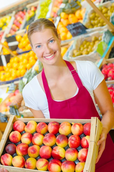 Winkelbediende houden lade van nectarines — Stockfoto