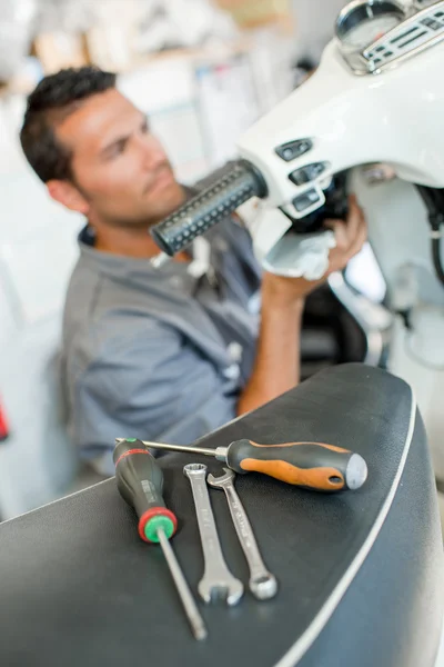 Meccanico esaminando uno scooter — Foto Stock