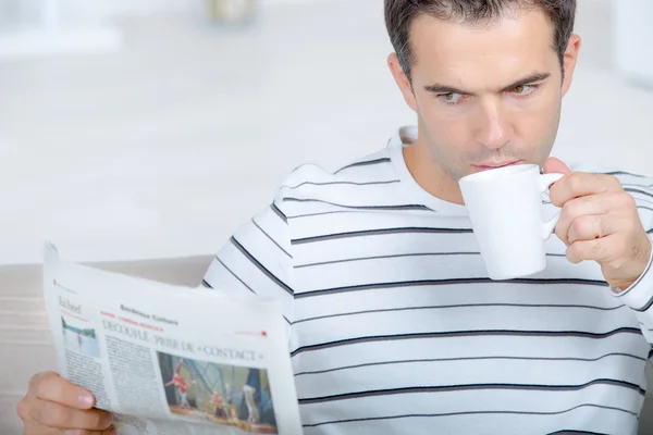 Läser tidningen som hennes drinkar sitt kaffe — Stockfoto