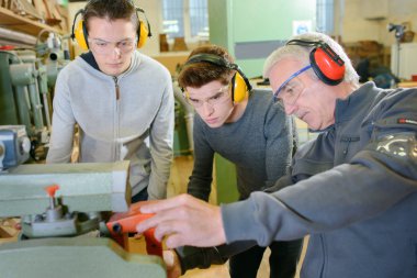 Senior carpenter with two learners clipart