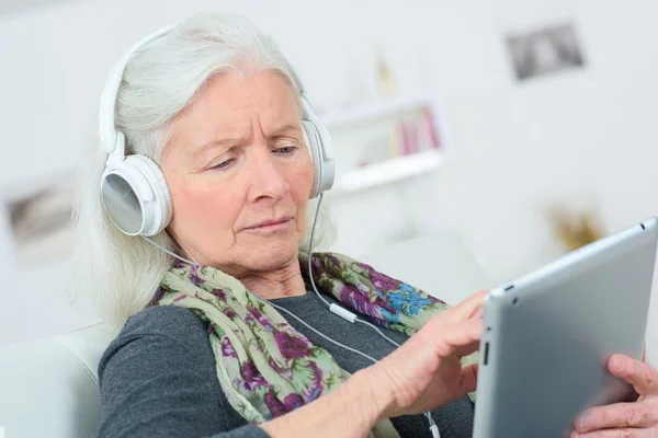 Senior senhora ouvindo música através de fones de ouvido — Fotografia de Stock