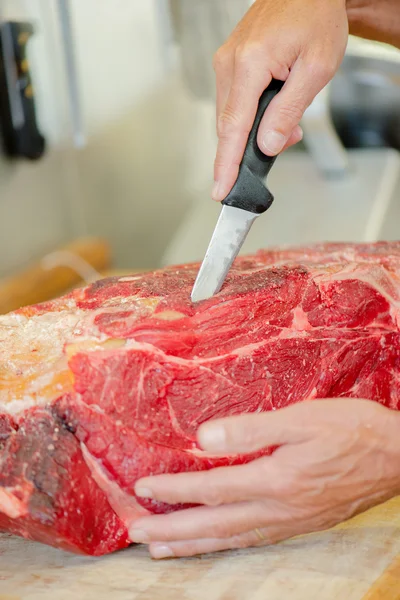 Butcher wearing a meat glove whilst preparing cut of beef — Stock Photo, Image