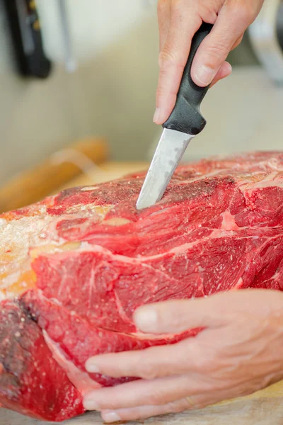 Butcher wearing a meat glove whilst preparing cut of beef — Stock Photo, Image