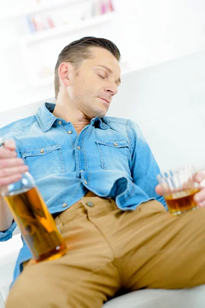 Homem dormindo com garrafa e vidro — Fotografia de Stock