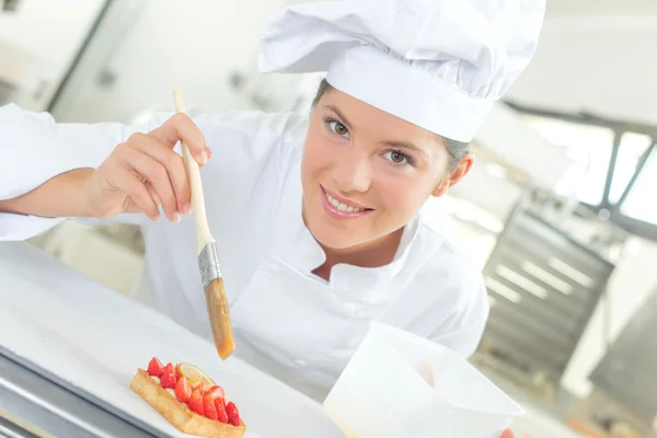 Baker borstelen van haar gebak — Stockfoto