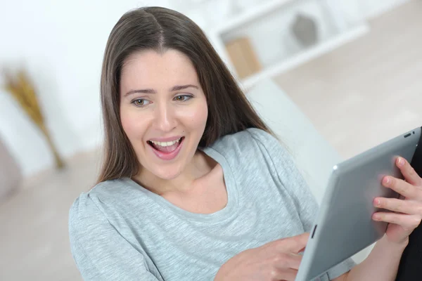 Brunette lachen om iets op haar Tablet PC — Stockfoto