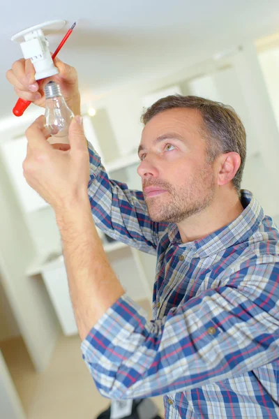 Elektriker wechselt eine Glühbirne — Stockfoto